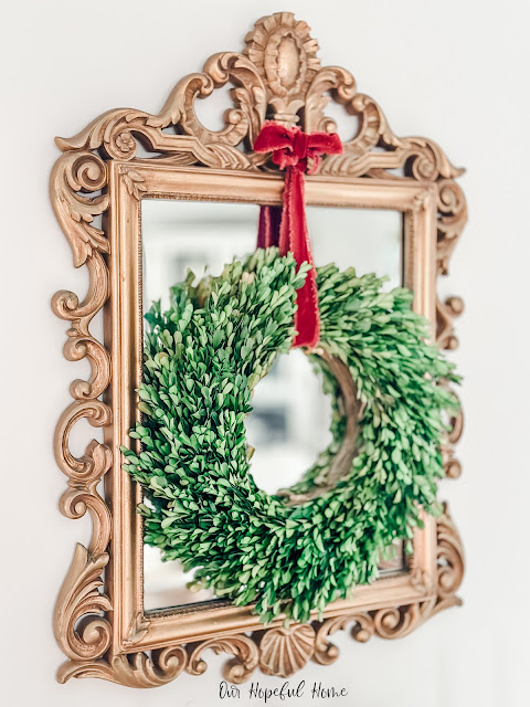 gold Windsor mirror with large boxwood wreath and velvet ribbon