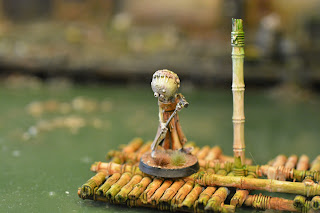 A photo of a gribbly mini with a bulbous head standing on a raft