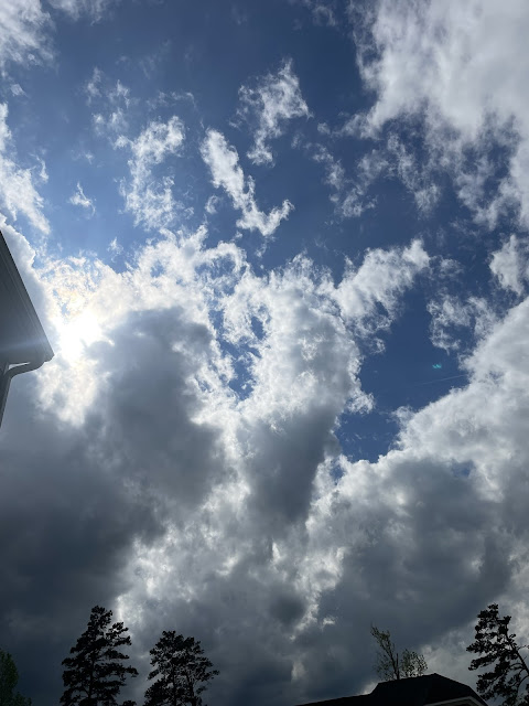 Clouds moving in from of the sun. As they pass, the sun highlights the edge of a couple of clouds. The sun, clouds, and deep blue sky all contrast against one another making a beautiful view.