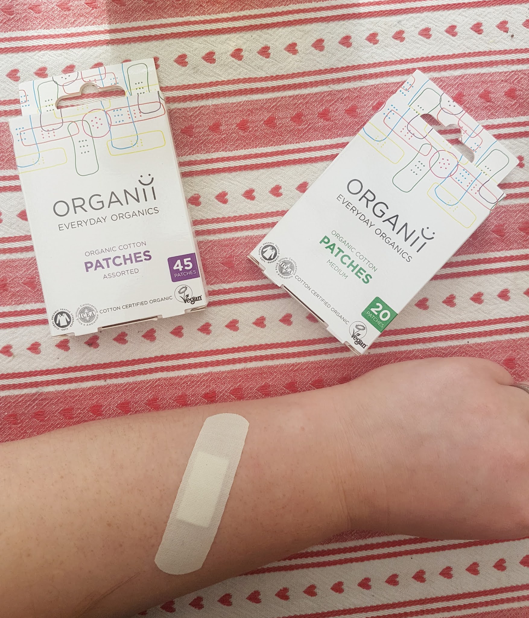 vegan cotton bandage on arm with two boxes of the Organii plastic free plasters sitting above