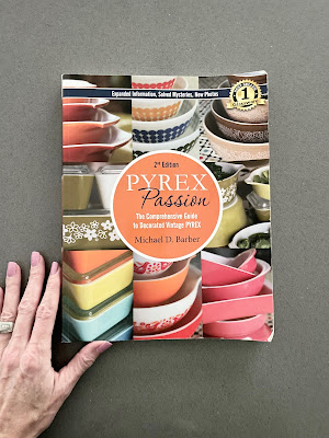 A hand holding a book called Pyrex Passion