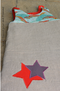 Turbulette en lin coloris naturel, coton japonais, violet au dos et rouge intérieur, appliqués étoiles, fermeture éclair beige sur le coté, pressions turquoises épaules, doublée en ouatine longueur 70 cm (0-3 mois).