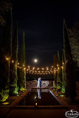 bride and groom kissing at the end of reflection pool at night with marketlighting at bella collina