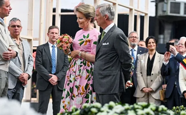 Queen Mathilde wore a degrade magnolia flower print belted poplin dress from Oscar de la Renta. Gold earrings and green pumps by Natan