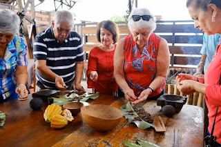 Un grupo de visitantes mayores se divierte y concentra en la preparación del chocolate con cacao