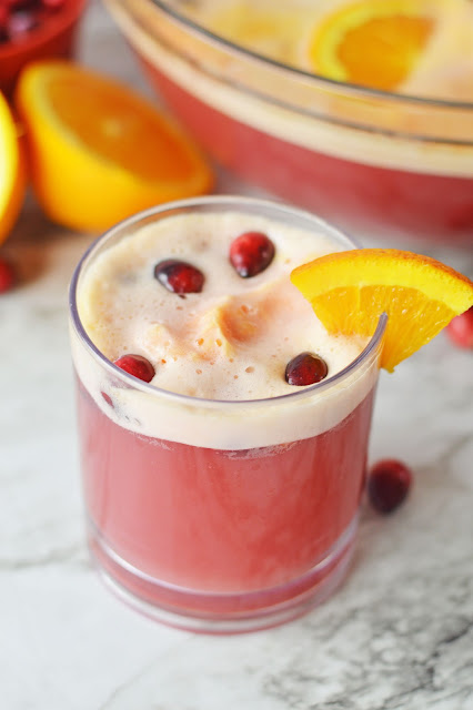 punch in a clear glass with cranberry and orange slice garnish.