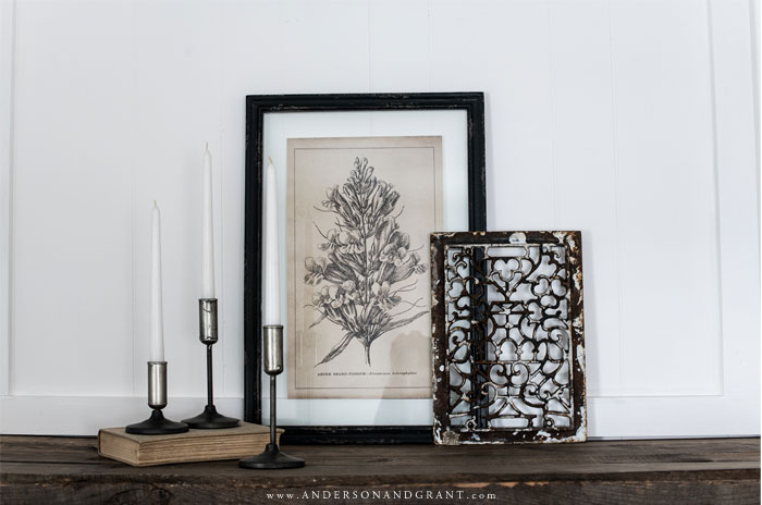 Collection of candlesticks, botanical print, and metal register cover.