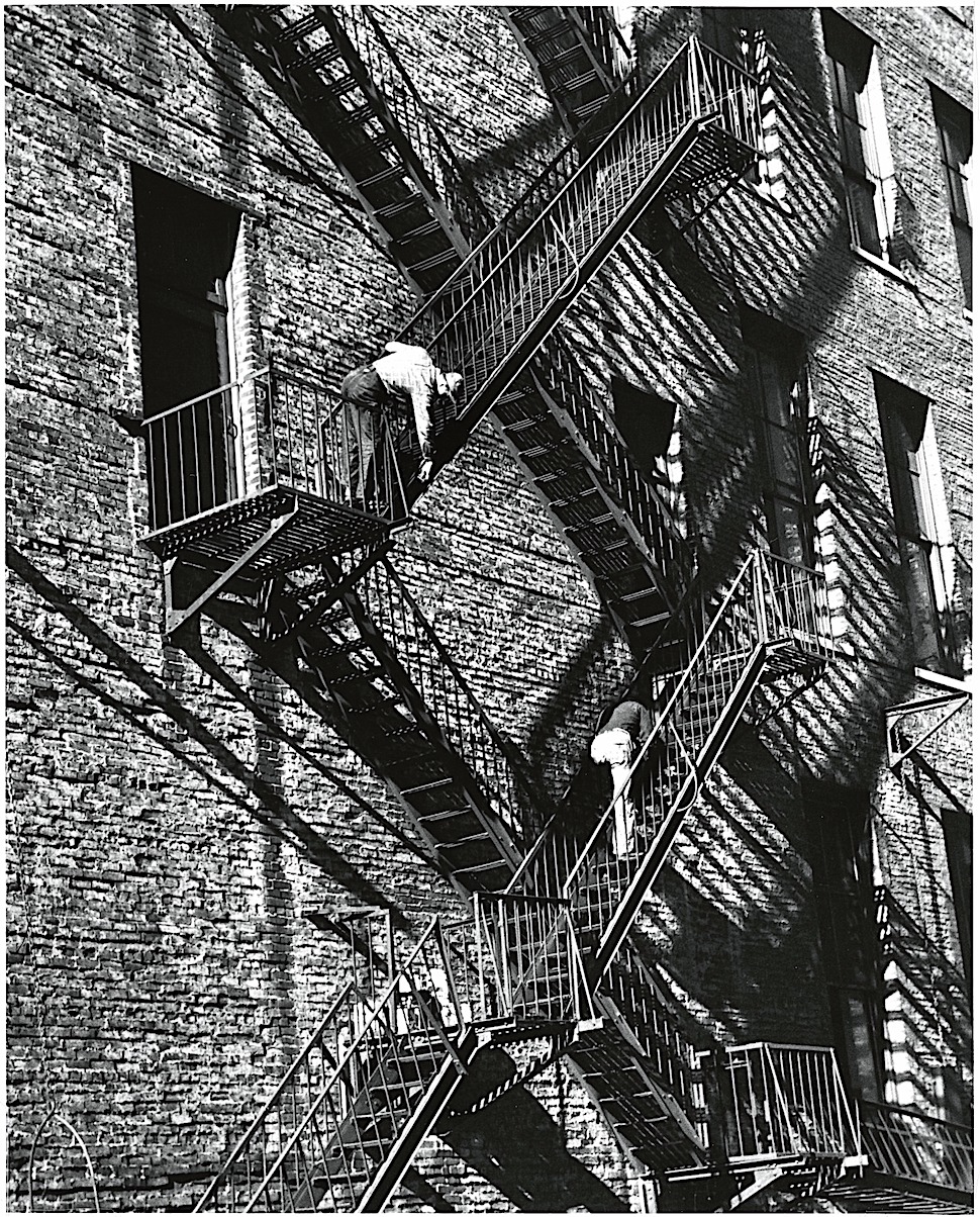 an André Kertész 1949 photograph of men working on a fire escape with long shadows