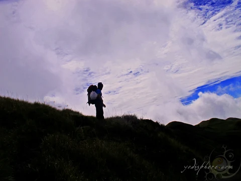 Mountaineer standing at the horizon between mountain ridge and sky