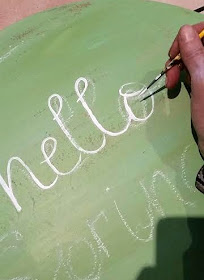 hand paint a sign for spring on an old round tabletop 