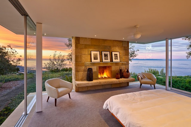 Home Bedroom with Wide Wooden Bed and White Quilt facing the Stone Fireplace