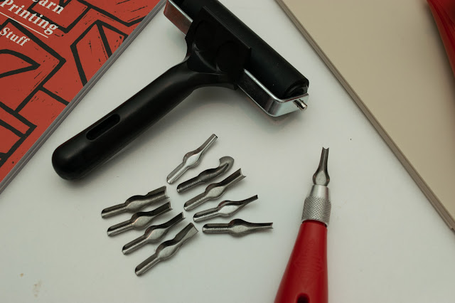 Lino printing roller and lino cutter with blades.