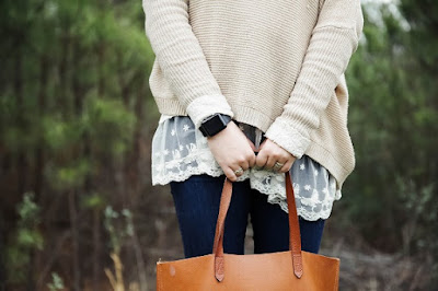 Woman holding leather tote bag in forest