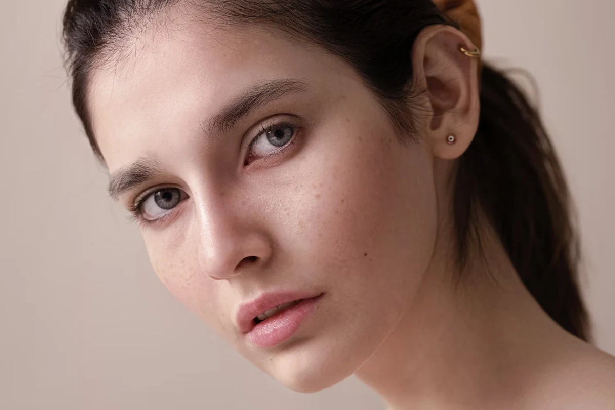 close-up portrait of woman's face with a no-makeup makeup look, clean skin and ponytail