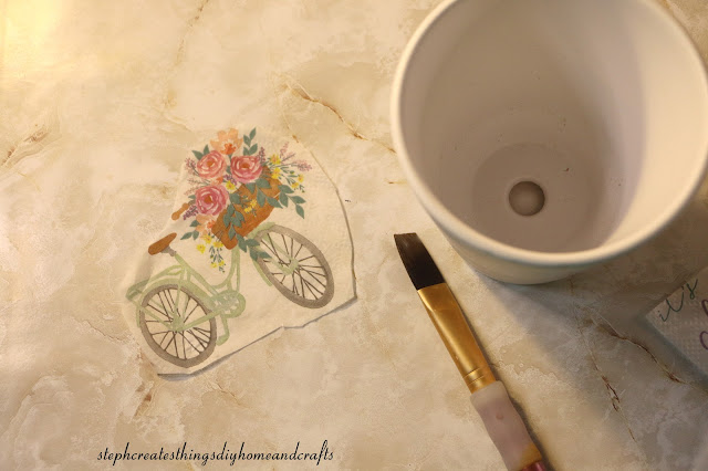 Cut out of decorative napkin, paintbrush, and garden pot on a table