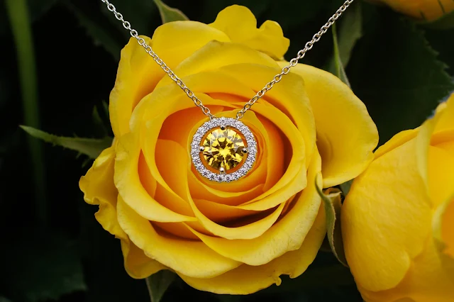 A close up photo of a yellow rose with the Gwen pendent resting on the centre of the rose