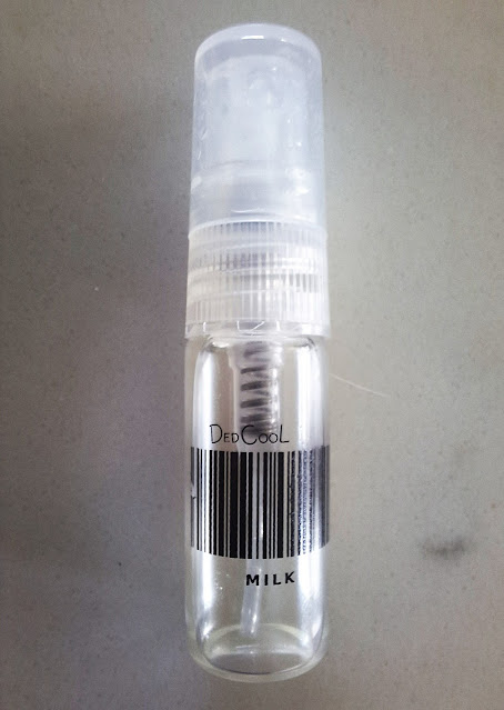 Dedcool Milk Sample, clear glass bottle with plastic top/nozzle, black upper and lowercased font and barcode scan design.