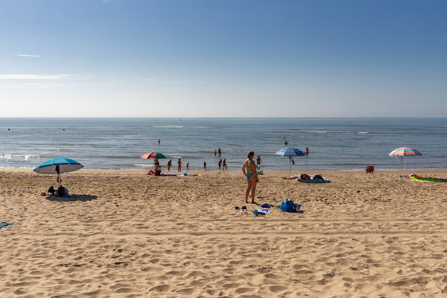 Playa de arena fina con gente y el agua del mar con el cielo azul de fondo