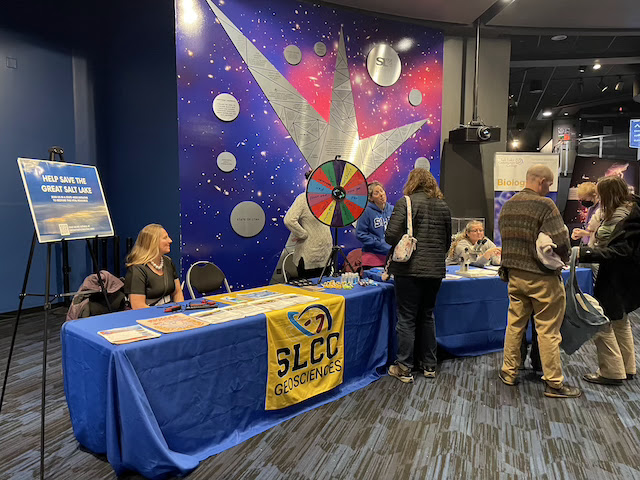 A woman sitting at a table talking with people about science