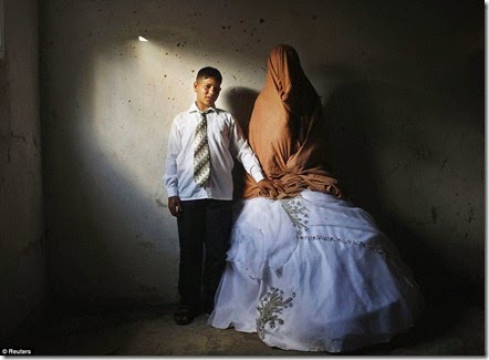 Palestinian groom Ahmed Soboh, 15 and his bride Tala, 14, stand inside Tala's house during their wedding party in the town of Beit Lahiya, near the border between Israeli and Gaza Strip September  - Copy