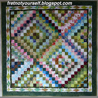 Scrappy Trip baby quilt with diamond border. Green and pink