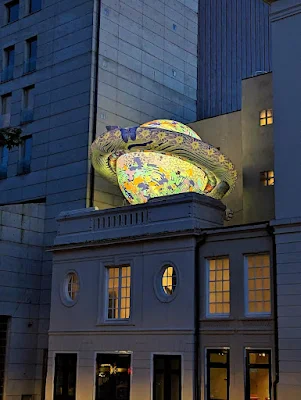 Inflatable Saturn on top of a building lit up after dark in The Hague