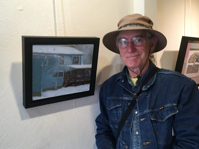 Artist posing with painting of snow blowing off roof