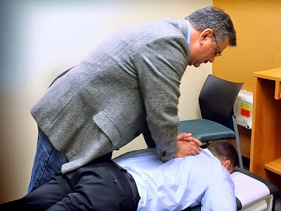 Chiropractor treating a male patient laying on his stomach