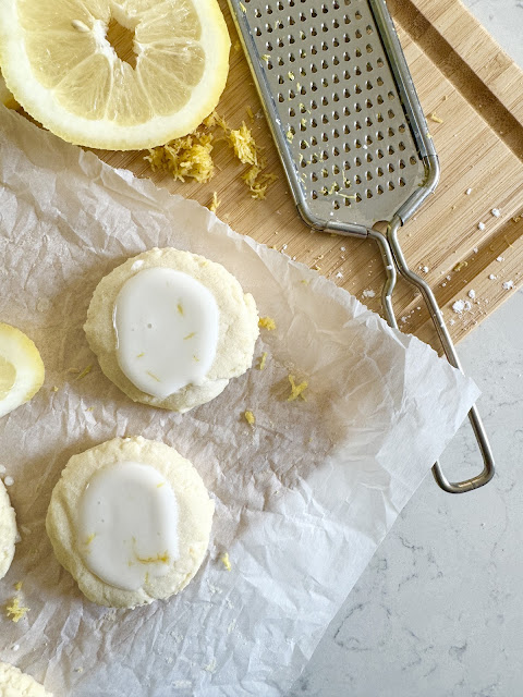 Lemon Meltaway Cookies on parchment paper next to lemons and a microplane.
