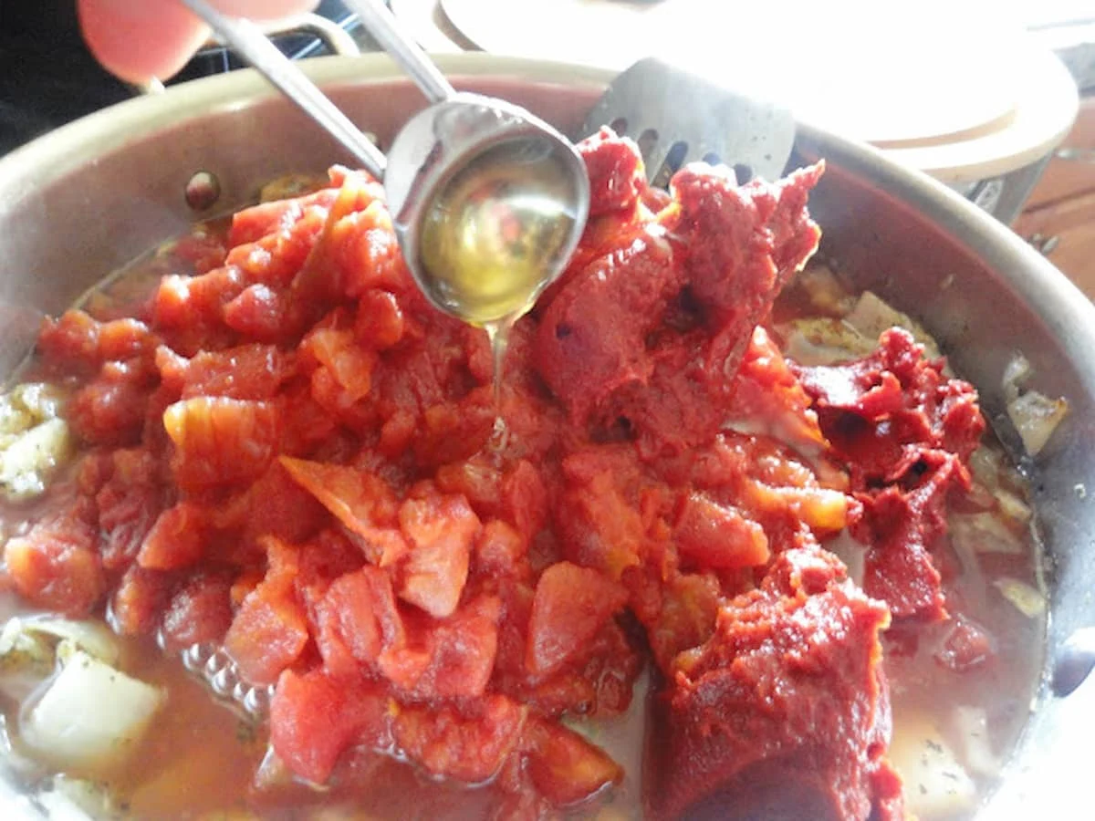 Tomato, tomato paste, honey and water added to sautéed onions to make Meatball Subs.