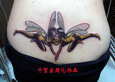 A lower back tattoo showing two fairies kissing.