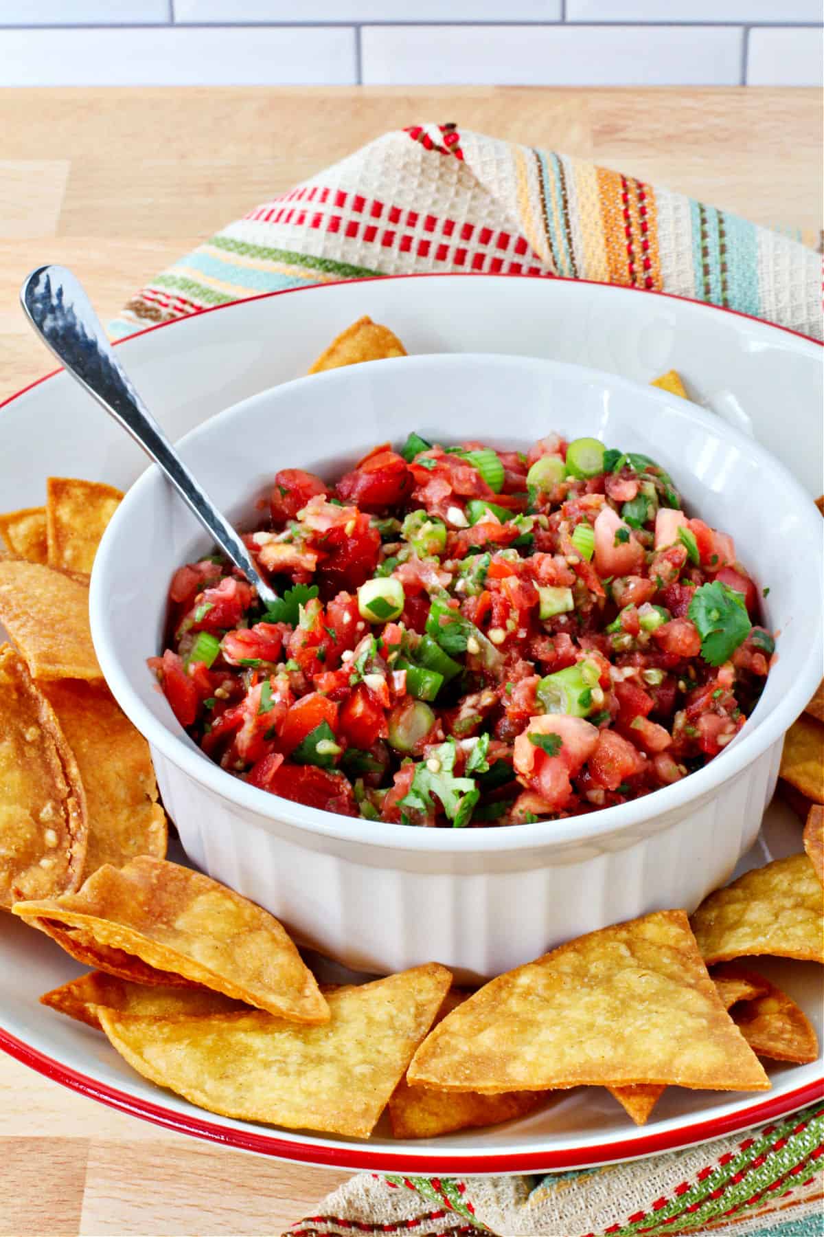 Fresh Tomato Salsa in a white bowl with a spoon in the bowl.