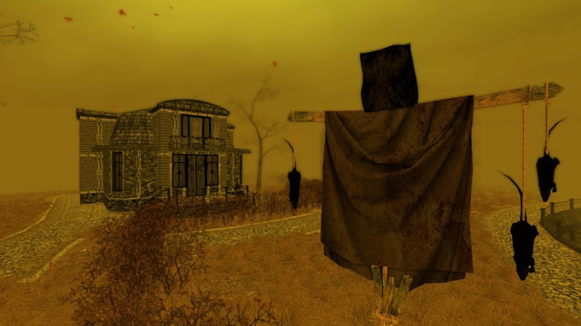 An image from the video game, 'Pathologic'. The sky is yellow. There is a brick house in the background. In the foreground, there is a scarecrow with rats hung from its arms by their tails.