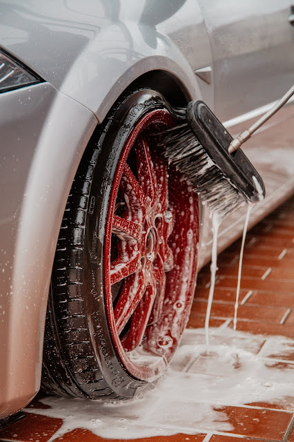 Washing red car wheel with brush:Photo by Adrian Dascal on Unsplash