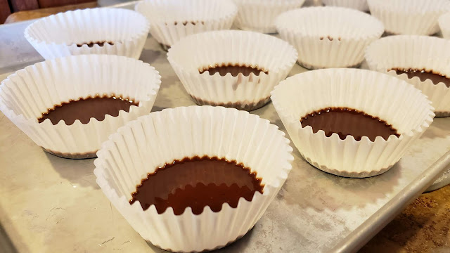 Chocolate filled cupcake liners on a baking sheet.