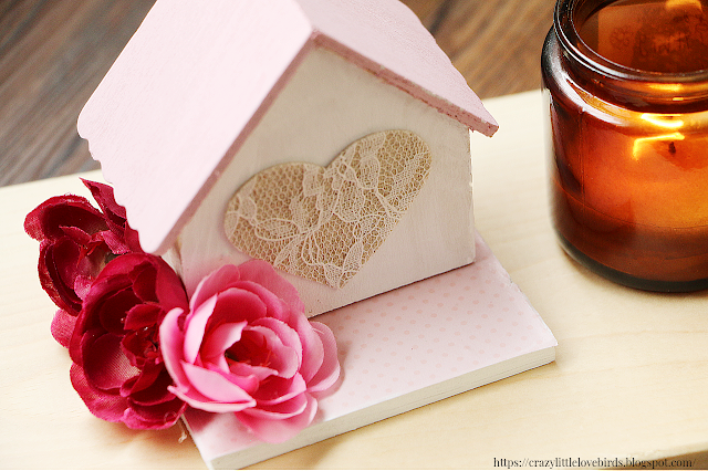 Close up of mini painted house with faux floral and fabric heart