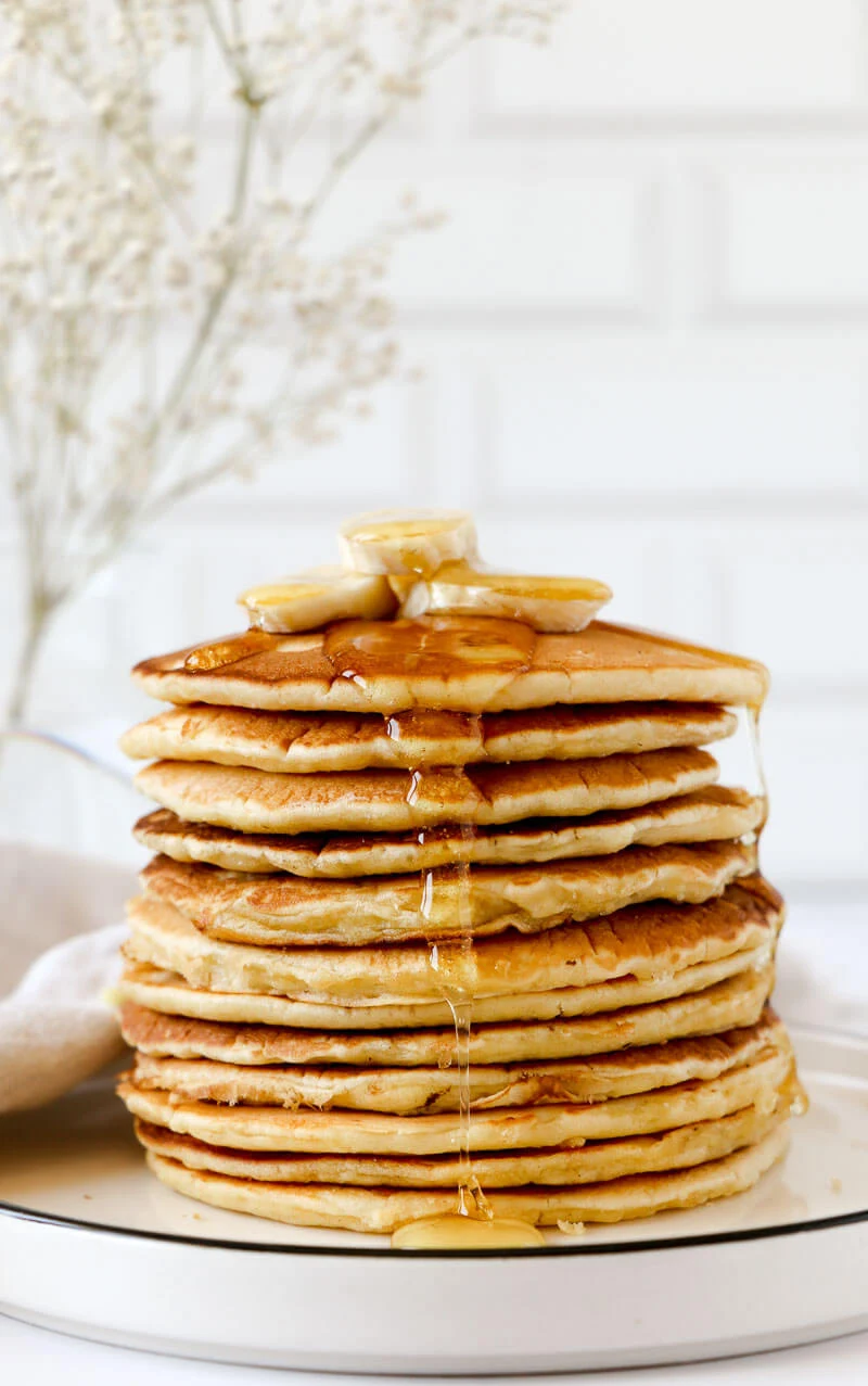 A stack of finished cassava flour pancakes with drizzle of maple syrup.