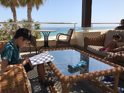 Children by a hotel swimming pool reading