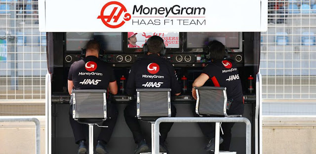 Haas pit wall staff looking at the Losers League website on their tiny pit gantry