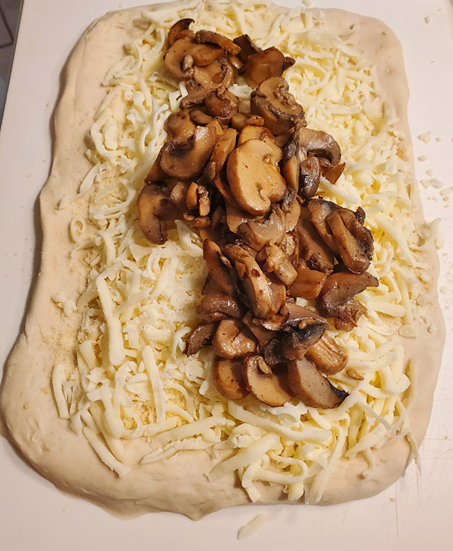 dough rolled out with cheese and mushroom marsala for pizza rolls