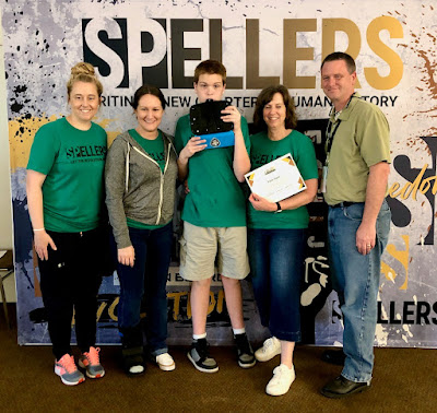 Five people standing in front of sign reading Spellers