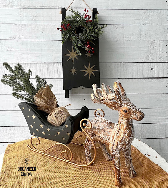 Photo of a thrifted sleigh and a sled upcycled with black chalk paint and gold stars.