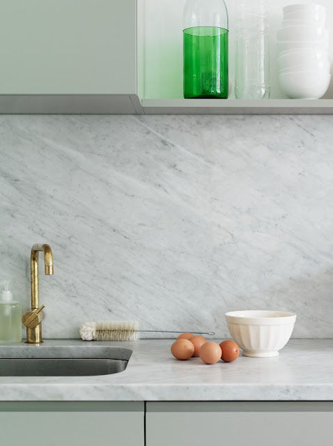 kitchen with gold faucet, mint cabinets, marble slab backsplash and matching counter