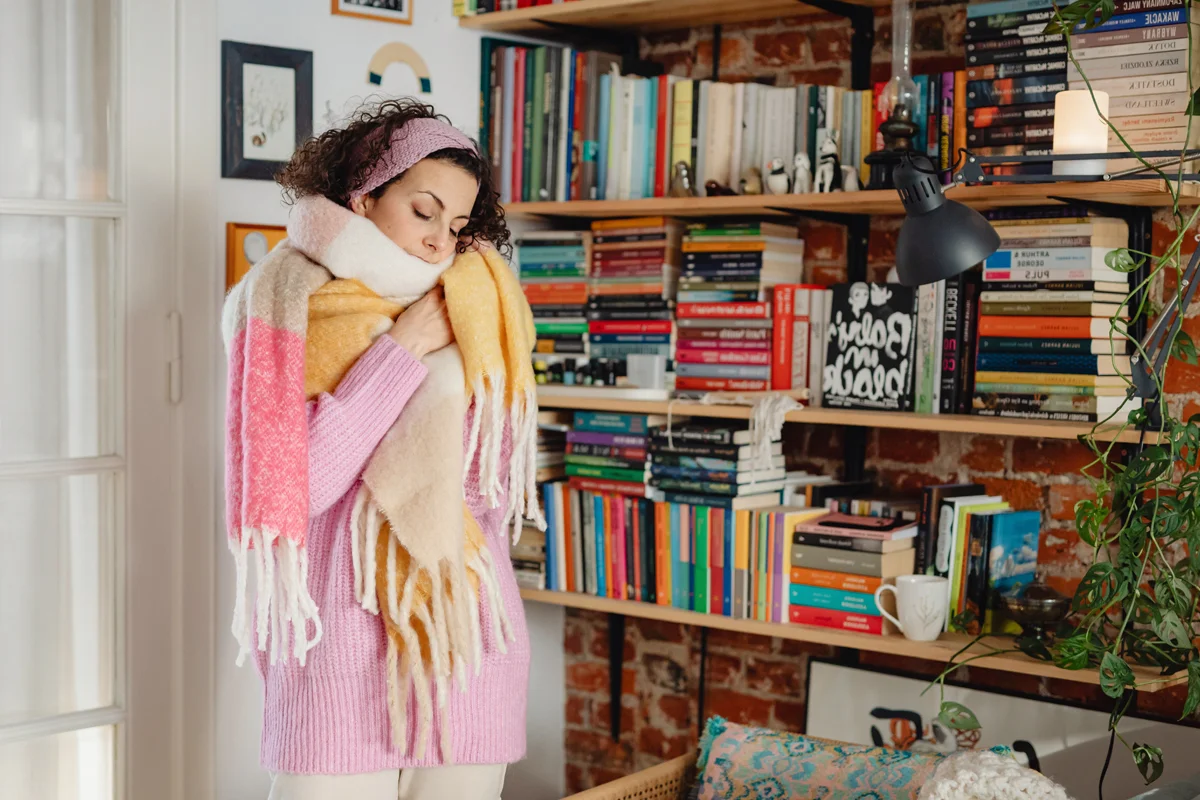 woman wearing layers of warm clothes at home
