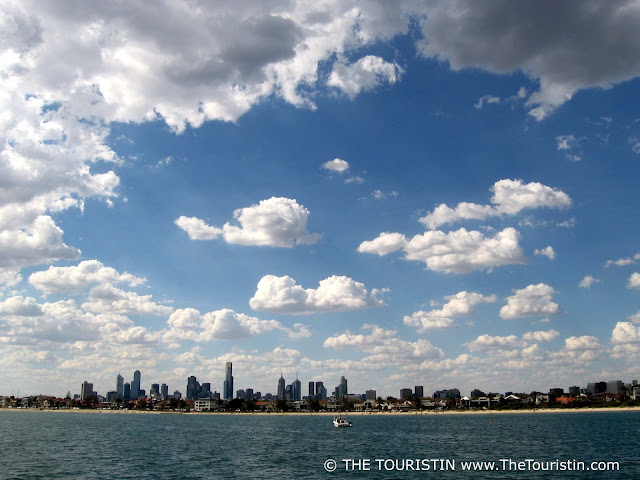 Skyline of a city in the background of the ocean and a white sandy beach..