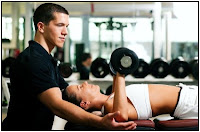 White male personal trainer helping a white female exercsie