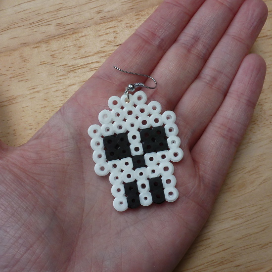 Black and white beaded skull design earring held in the hand