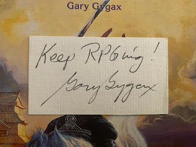 New Infinities Productions, Inc. business card, signed on reverse by Gary Gygax with "Keep RPGing! Gary Gygax"