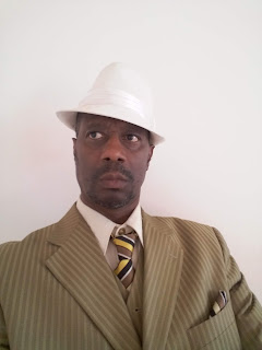 Picture of the author of the book, wearing a suit & tie and a white felt hat