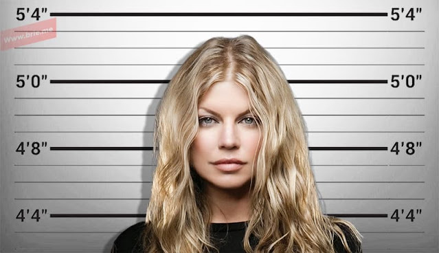 Fergie posing in front of a height chart background